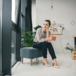 Woman contemplating looking out window with cup of coffee