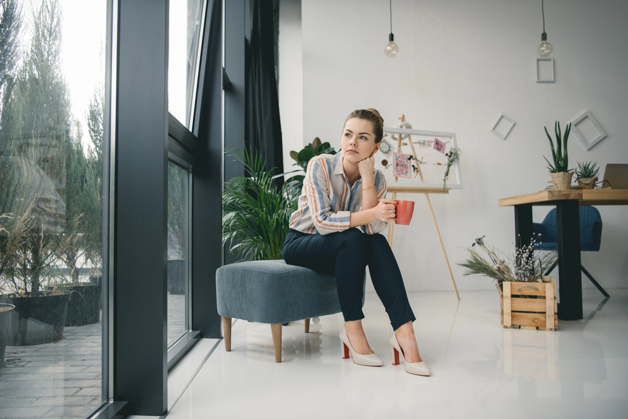 Woman contemplating looking out window with cup of coffee