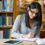Woman with black hair studying in library setting