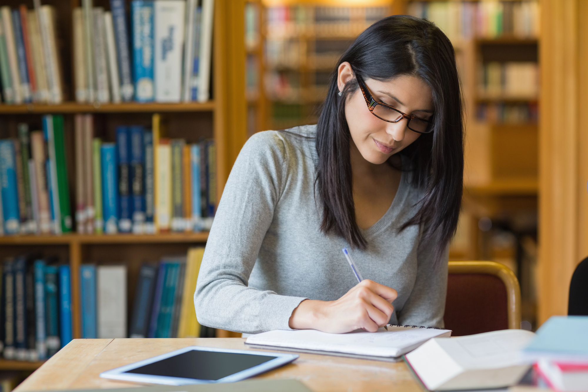Woman with black hair studying in library setting